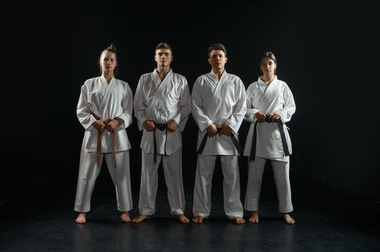 Four martial artists standing side by side in Gi uniforms