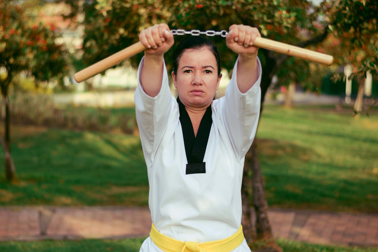 Martial artist in dobok holding up nunchucks